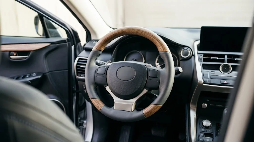 Interior view of an AKIUMI custom steering wheel for a Lexus NX with matte carbon trim, perforated black leather grips and blue stitching